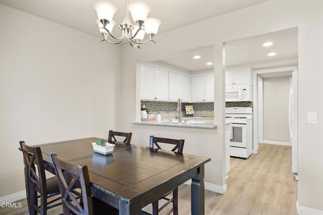 dining area featuring a notable chandelier, sink, and light wood-type flooring