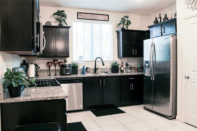 kitchen featuring light stone countertops, appliances with stainless steel finishes, sink, and light tile patterned floors