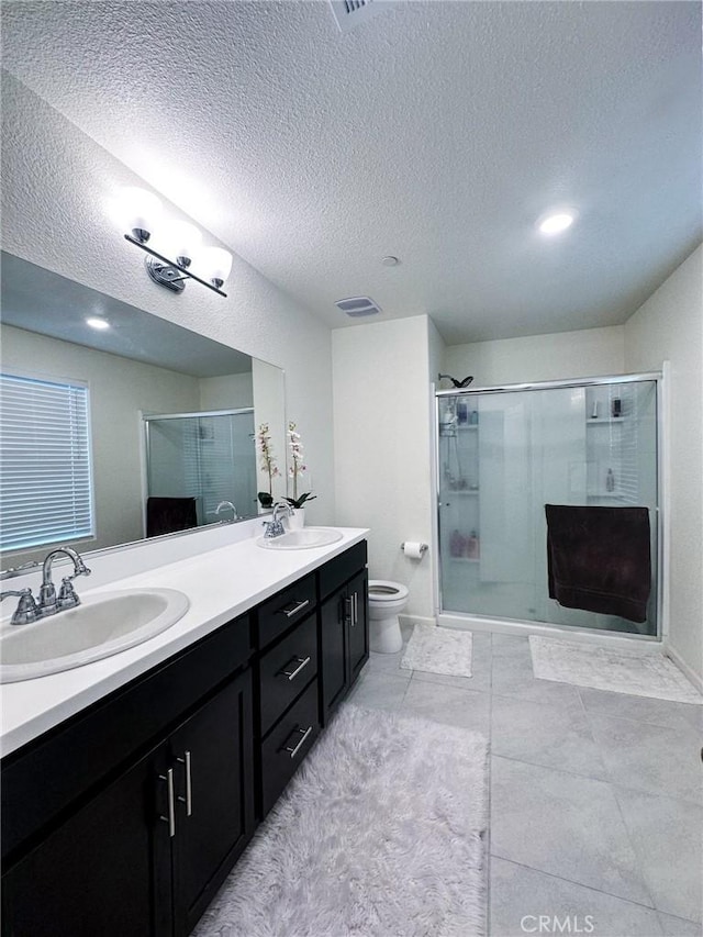 bathroom with vanity, a textured ceiling, toilet, and walk in shower