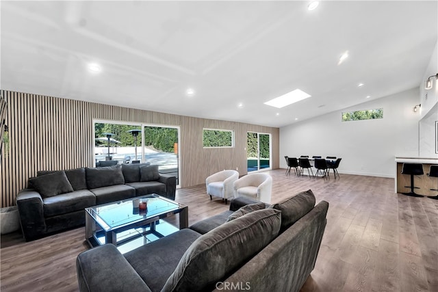 living room with vaulted ceiling with skylight and light wood-type flooring