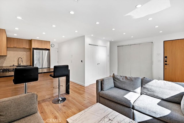 living room featuring sink and light hardwood / wood-style flooring