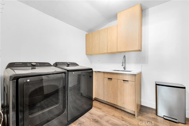 laundry area with cabinets, independent washer and dryer, light hardwood / wood-style floors, and sink