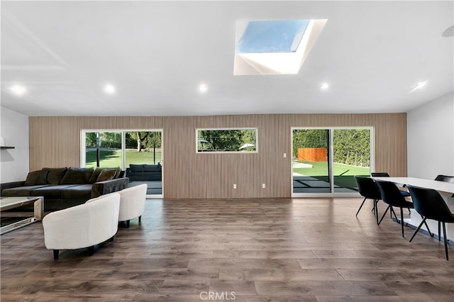 living room featuring a skylight, a wealth of natural light, and dark hardwood / wood-style floors