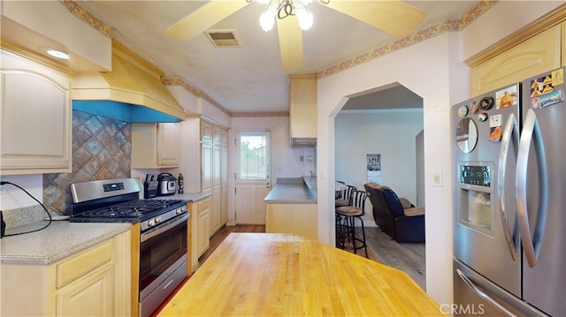 kitchen with cream cabinetry, appliances with stainless steel finishes, tasteful backsplash, and wood-type flooring