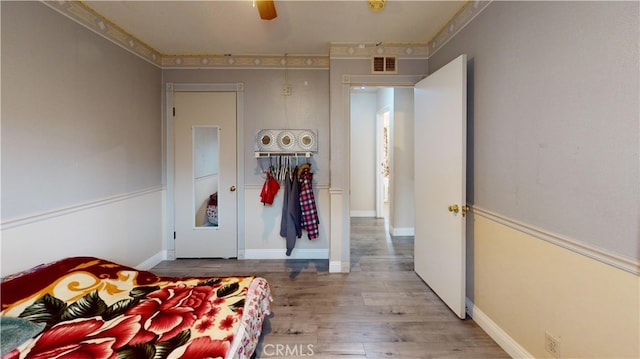 bedroom with hardwood / wood-style floors, ceiling fan, and ornamental molding