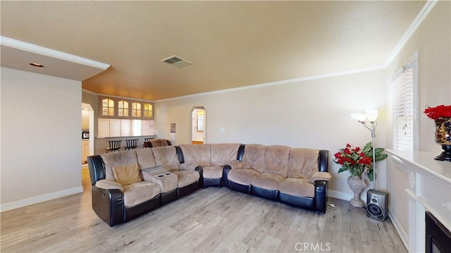 living room featuring a wealth of natural light, ornamental molding, and light hardwood / wood-style floors