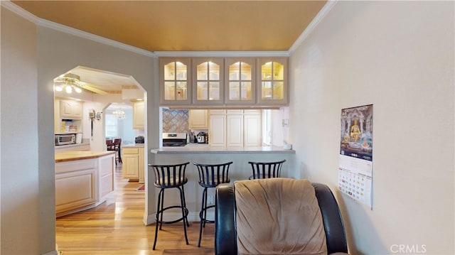 dining room with light hardwood / wood-style floors, ornamental molding, and ceiling fan