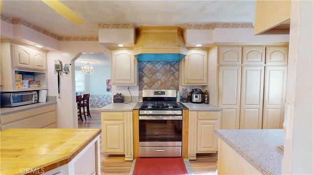 kitchen featuring light wood-type flooring, stainless steel appliances, custom range hood, and tasteful backsplash