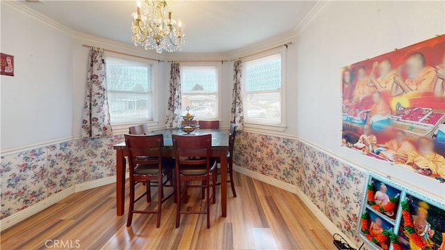 dining area with wood-type flooring, ornamental molding, and a notable chandelier