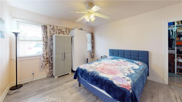 bedroom featuring a closet, ceiling fan, light hardwood / wood-style flooring, and multiple windows