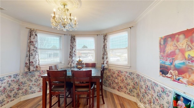 dining area with crown molding, hardwood / wood-style flooring, and an inviting chandelier