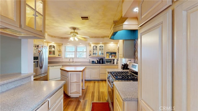 kitchen featuring ceiling fan, sink, a kitchen island, light hardwood / wood-style flooring, and stainless steel appliances