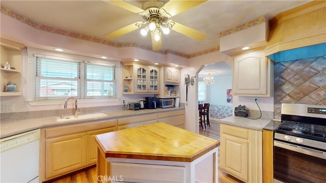 kitchen featuring wood counters, a kitchen island, white dishwasher, sink, and gas range