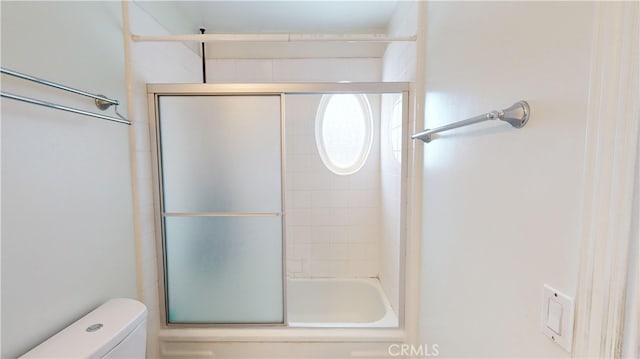 bathroom featuring bath / shower combo with glass door and toilet