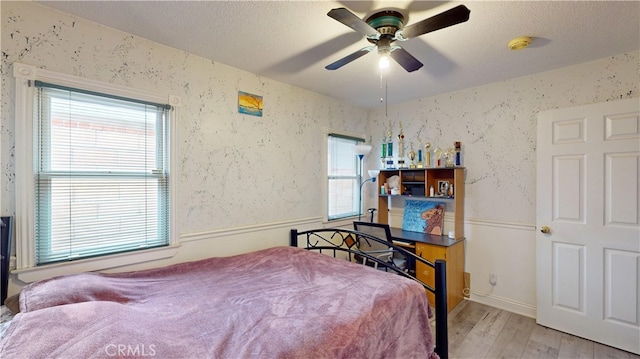 bedroom with ceiling fan, light hardwood / wood-style floors, and multiple windows