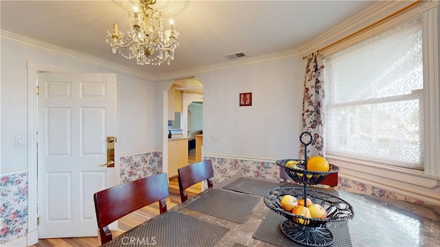 dining space featuring wood-type flooring, a notable chandelier, and ornamental molding