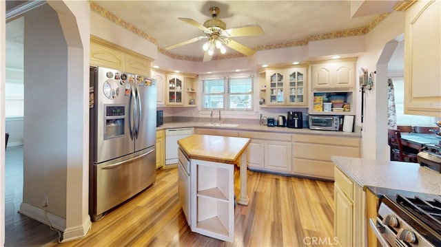 kitchen featuring ceiling fan, appliances with stainless steel finishes, sink, light wood-type flooring, and a kitchen island