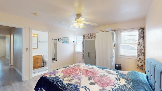 bedroom with light wood-type flooring, ceiling fan, and ensuite bath