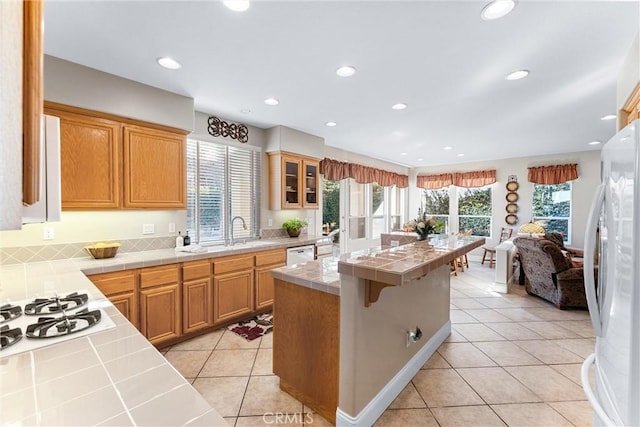 kitchen with light tile patterned flooring, white appliances, tile countertops, and a breakfast bar