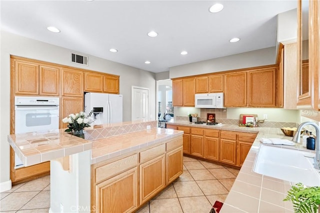 kitchen with white appliances, tile counters, sink, a kitchen island, and light tile patterned flooring