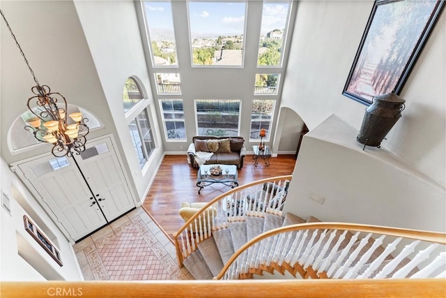 staircase featuring hardwood / wood-style floors, a towering ceiling, and an inviting chandelier