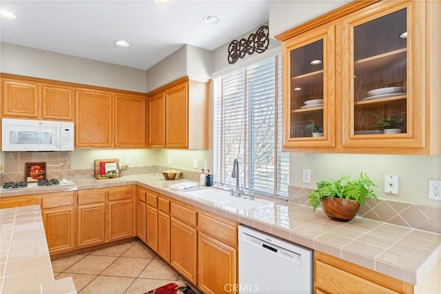 kitchen featuring sink, white appliances, light tile patterned floors, and tile counters