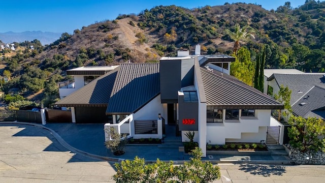 view of front of house featuring a standing seam roof, metal roof, a chimney, and a mountain view