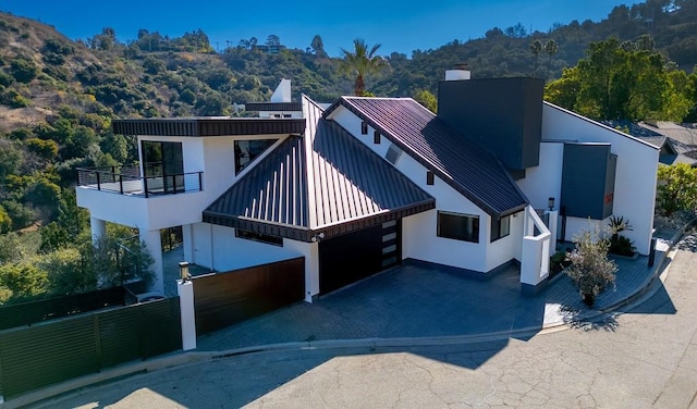 view of front of property with driveway, a standing seam roof, a balcony, and stucco siding