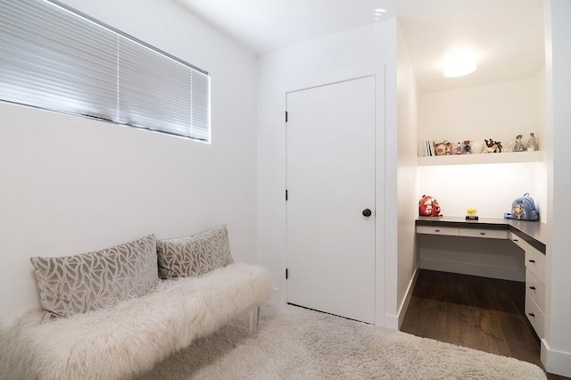 sitting room with built in desk and wood finished floors