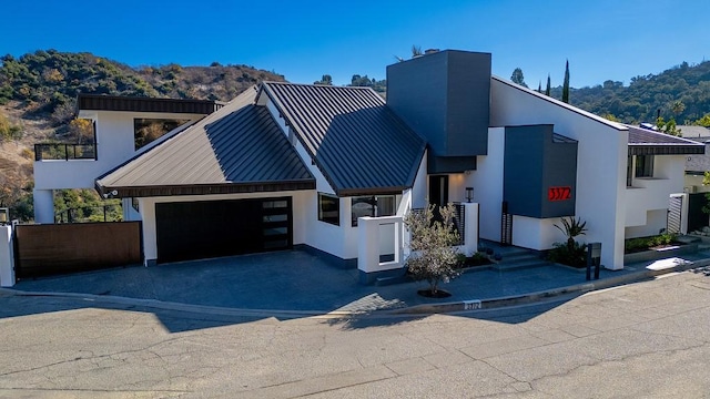 view of front of home featuring metal roof, an attached garage, a mountain view, stucco siding, and a standing seam roof