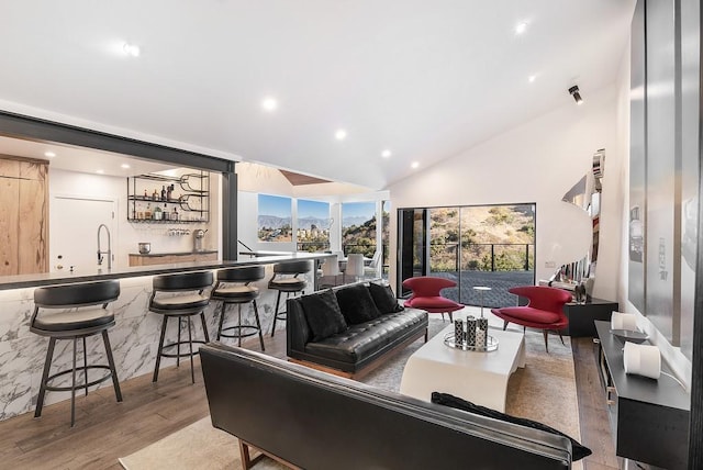 living room with lofted ceiling, indoor wet bar, wood finished floors, and recessed lighting