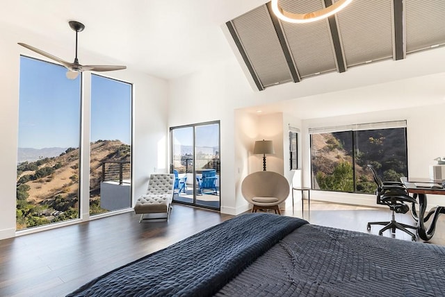 bedroom with access to outside, a high ceiling, baseboards, and wood finished floors