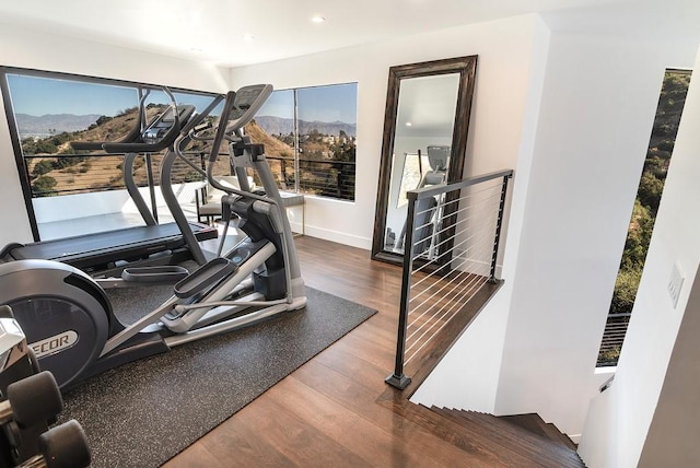 workout area with recessed lighting, a mountain view, baseboards, and wood finished floors