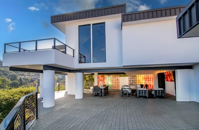 back of property featuring a balcony, an outdoor hangout area, and stucco siding