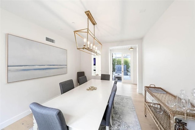 dining area featuring light wood-type flooring and an inviting chandelier