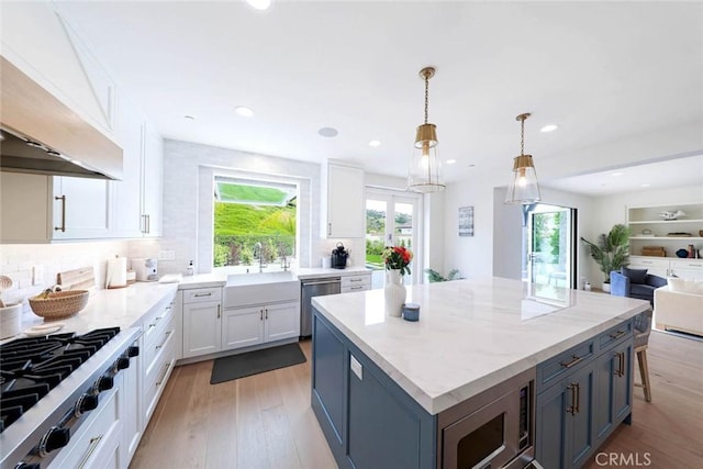 kitchen with pendant lighting, white cabinets, a center island, custom exhaust hood, and stainless steel appliances