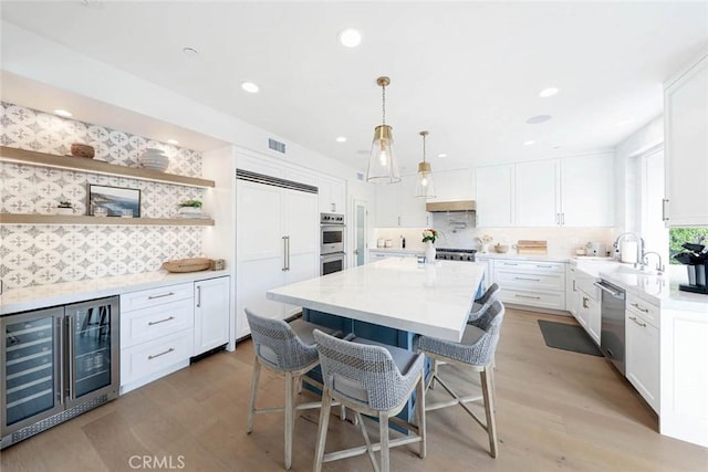 kitchen with a kitchen breakfast bar, wine cooler, white cabinetry, light stone counters, and stainless steel appliances