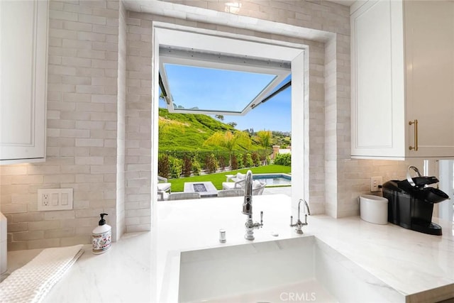 details with light stone countertops, sink, white cabinetry, and backsplash