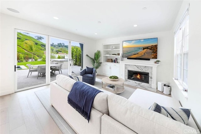 living room with built in features, light hardwood / wood-style floors, and a fireplace