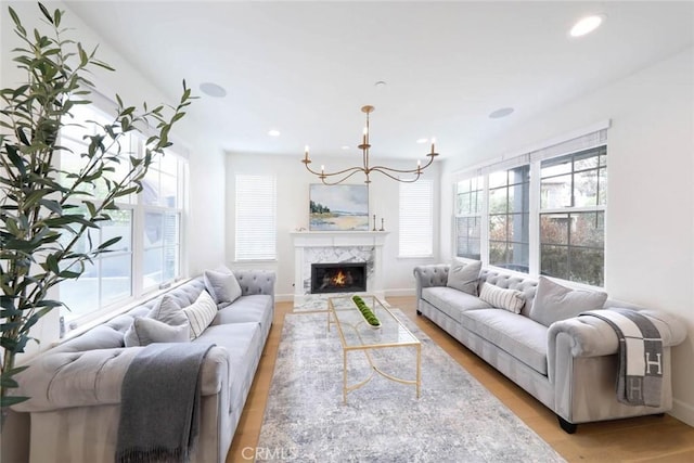 living room featuring a premium fireplace, a chandelier, and light hardwood / wood-style floors