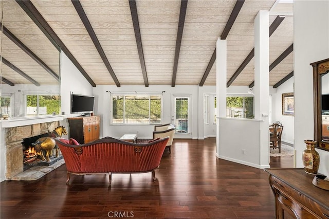 living room with vaulted ceiling with beams, dark wood-type flooring, a fireplace, and a healthy amount of sunlight