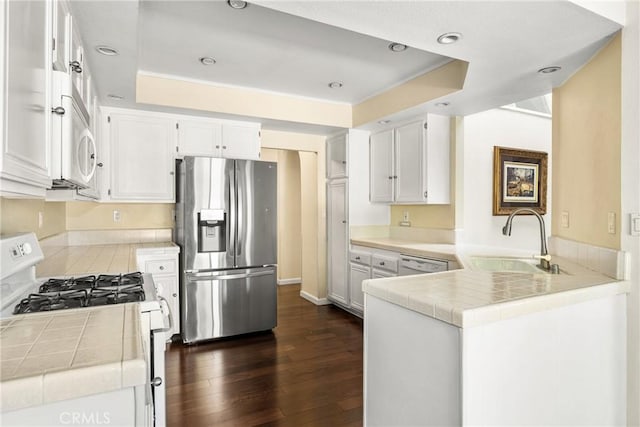 kitchen with white appliances, kitchen peninsula, sink, and white cabinets