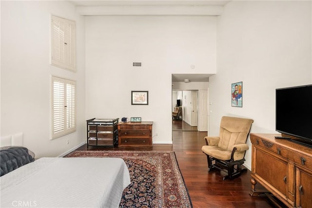 bedroom with a high ceiling and dark hardwood / wood-style floors