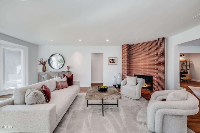 living room featuring a large fireplace, a healthy amount of sunlight, and light hardwood / wood-style floors