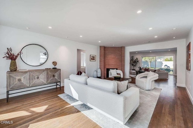 living room featuring a brick fireplace and wood-type flooring