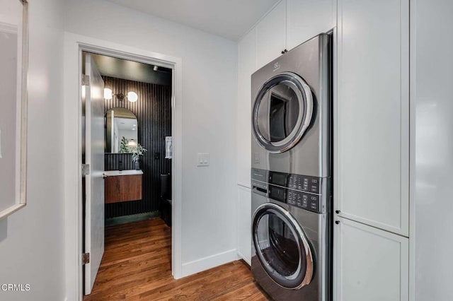 laundry area featuring stacked washer / dryer and hardwood / wood-style flooring