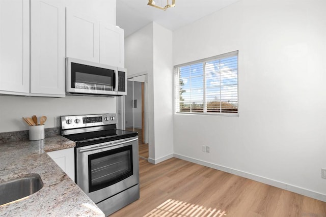 kitchen featuring light stone counters, white cabinetry, and appliances with stainless steel finishes