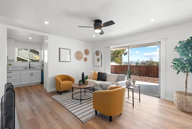 living room with sink, light hardwood / wood-style flooring, and ceiling fan