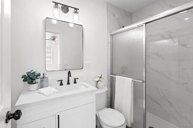 bathroom featuring vanity, toilet, ceiling fan, and a shower with shower door