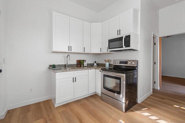 kitchen featuring sink, stainless steel electric stove, white cabinetry, and light hardwood / wood-style flooring